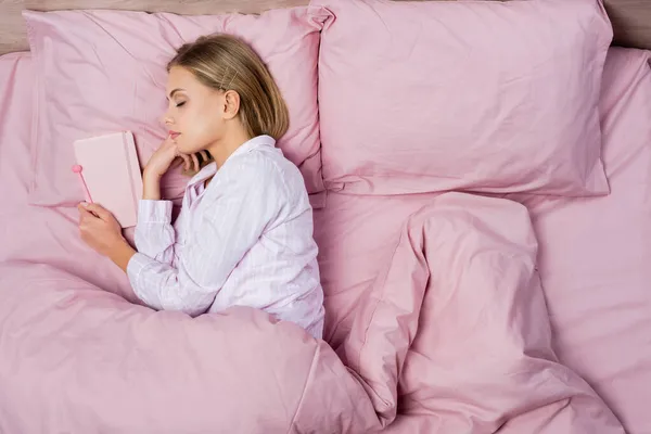 Top view of woman sleeping near notebook on bed at home — Stock Photo