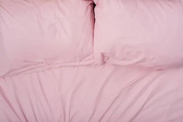 Top view of pillows on pink bedding on bed — Stock Photo