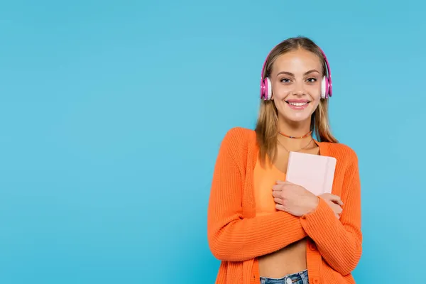 Mujer rubia alegre en auriculares con portátil aislado en azul - foto de stock