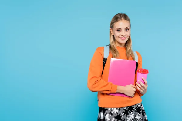 Positive Studentin mit Rucksack, Laptop und Kaffee zum Isolieren auf blauem Grund — Stockfoto