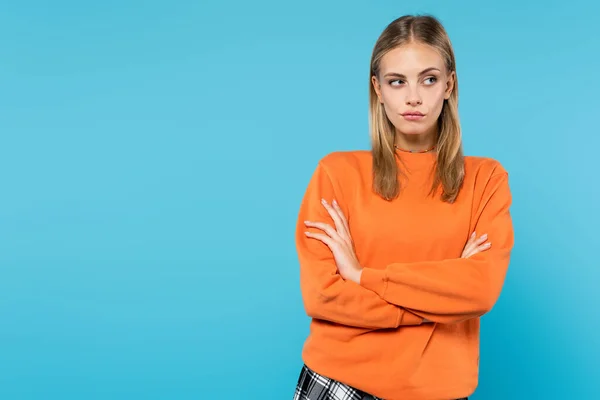 Skeptical woman standing with crossed arms isolated on blue — Stock Photo