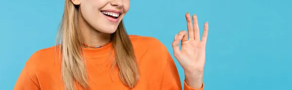 Cropped view of smiling young woman showing okay gesture isolated on blue, banner — Stock Photo