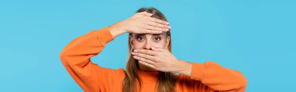 Femme blonde en sweat-shirt couvrant le visage avec les mains isolées sur bleu, bannière — Photo de stock