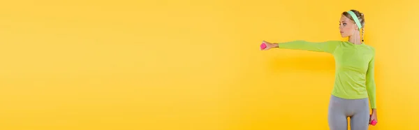 Schlanke Frau im Sportbekleidungstraining mit Kurzhanteln auf gelbem Banner — Stockfoto