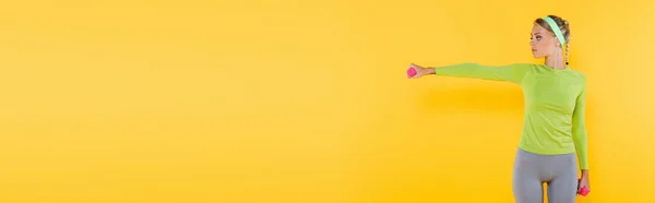 Slim woman in sportswear training with dumbbells isolated on yellow, banner — Stock Photo