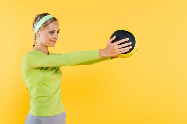 Femme heureuse en vert à manches longues t-shirt d'entraînement avec balle isolée sur jaune — Photo de stock