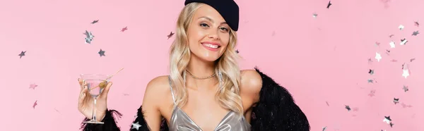 Cheerful and elegant woman with cocktail glass near sparkling confetti on pink, banner — Stock Photo