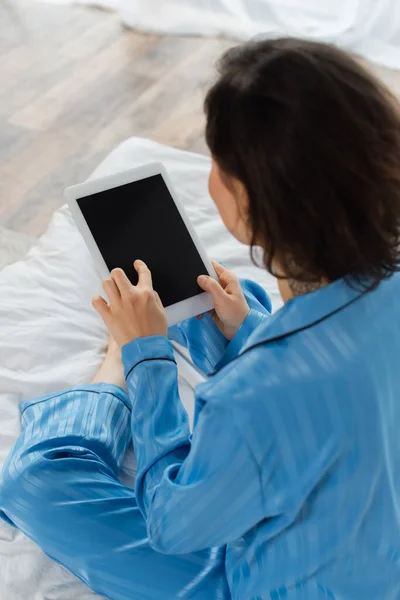 Vue grand angle de jeune femme floue en pyjama bleu à l'aide d'une tablette numérique avec écran blanc — Photo de stock