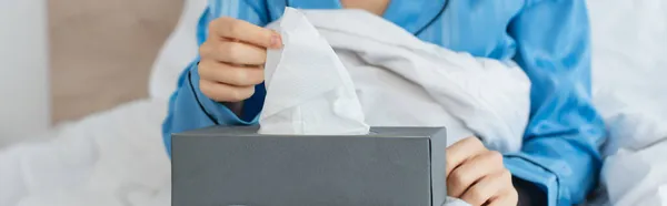 Vista recortada de la mujer joven que alcanza la servilleta en la caja de pañuelos, bandera - foto de stock