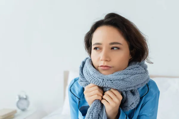 Jeune femme en écharpe tricotée regardant loin à la maison — Photo de stock