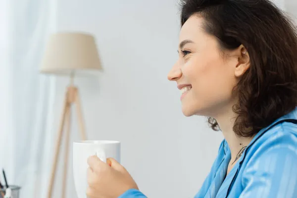 Vue latérale de la jeune femme heureuse tenant tasse de café — Photo de stock