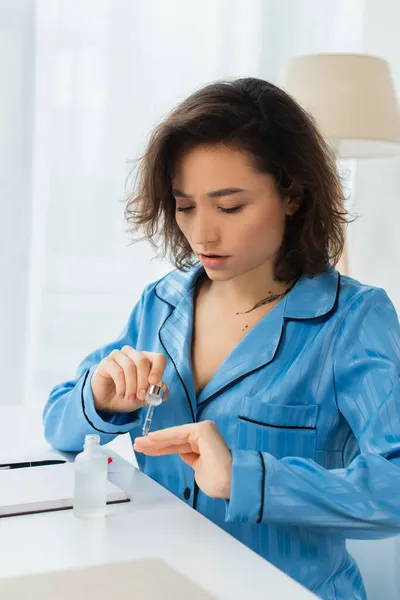 Jeune femme tenant une pipette avec de l'huile près des ongles — Photo de stock