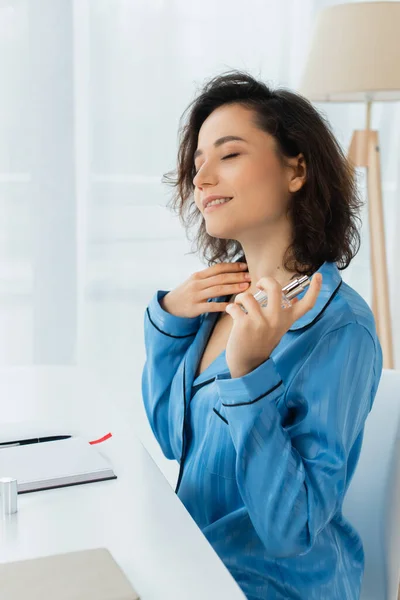 Pleased woman spraying perfume on neck — Stock Photo