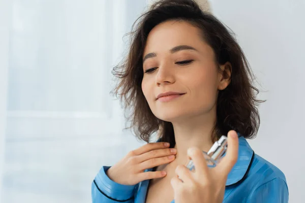 Pleased young woman spraying perfume on neck — Stock Photo