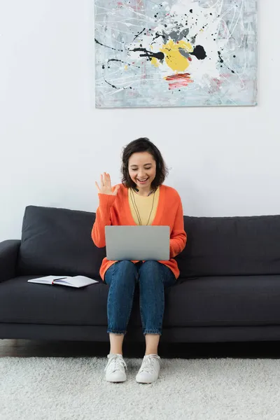 Cheerful operator in headset waving hand during video call — Stock Photo