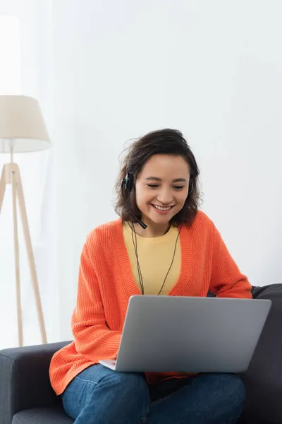 Cheerful operator in headset using laptop at home — Stock Photo