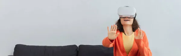 Young happy woman in vr headset gesturing during simulation game at home, banner — Stock Photo