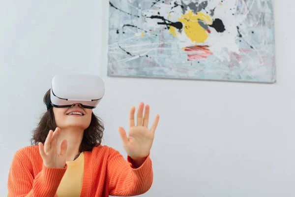 Jeune femme heureuse dans vr casque gestuelle pendant le jeu de simulation à la maison — Photo de stock