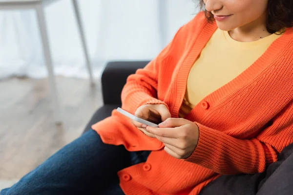 Vue recadrée de jeune femme textos sur téléphone portable dans le salon — Photo de stock