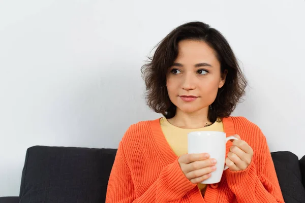 Junge Frau hält Tasse Kaffee in der Hand und schaut weg — Stockfoto