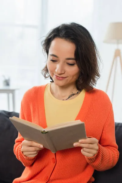 Pleased and tattooed woman reading book at home — Stock Photo