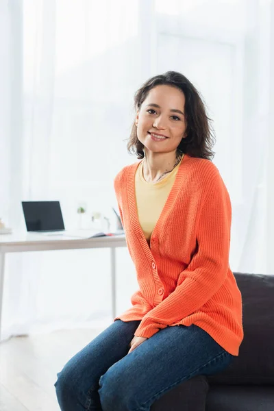 Felice e tatuato donna guardando la fotocamera mentre seduto sul divano a casa — Foto stock