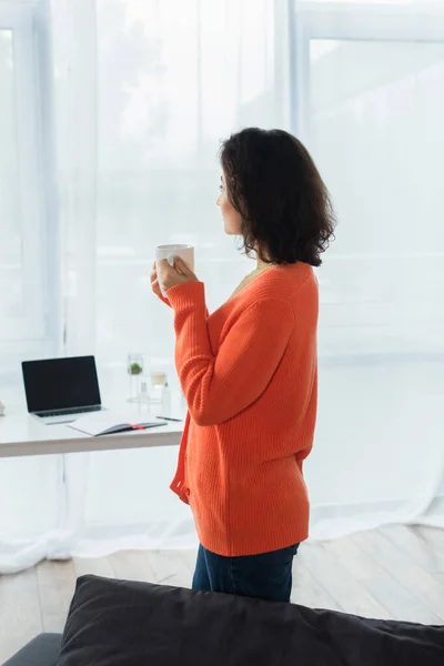 Side view of young woman holding cup of coffee at home — Stock Photo