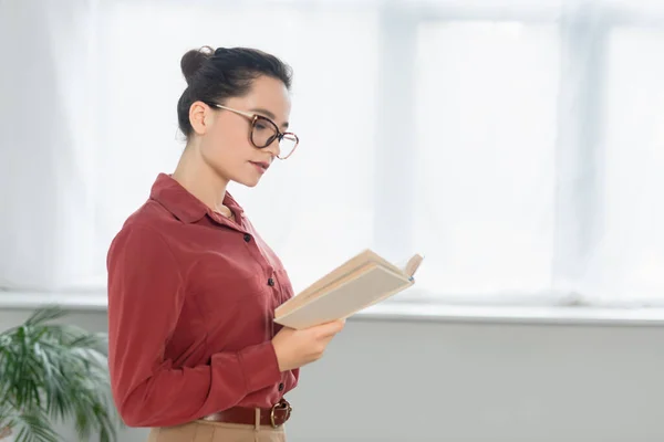 Joven profesor en anteojos lectura libro - foto de stock