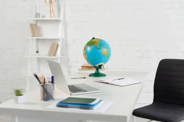 Globo, gadgets, papelería y cuadernos en el escritorio - foto de stock