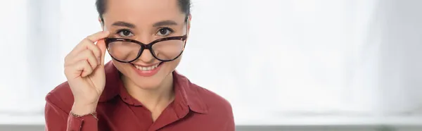 Glücklicher junger Lehrer, der seine Brille justiert und in die Kamera schaut, Banner — Stockfoto