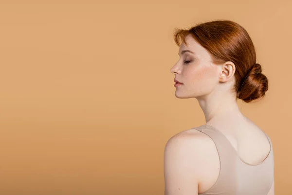 Vista laterale della giovane rossa in piedi isolata sul beige — Foto stock