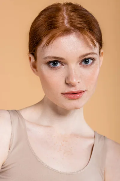 Young redhead woman with freckles on face looking at camera isolated on beige — Stock Photo