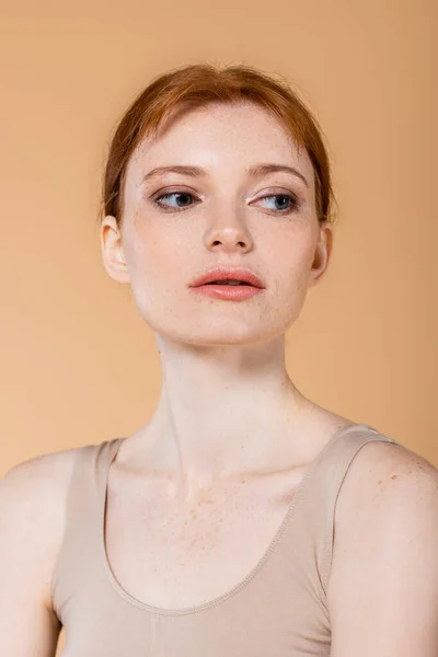 Jolie femme avec des taches de rousseur sur la peau regardant loin isolé sur beige — Photo de stock