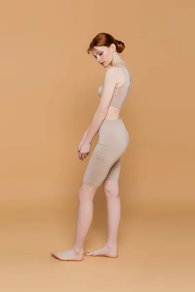 Donna scalza in alto e pantaloncini in piedi su sfondo beige — Foto stock