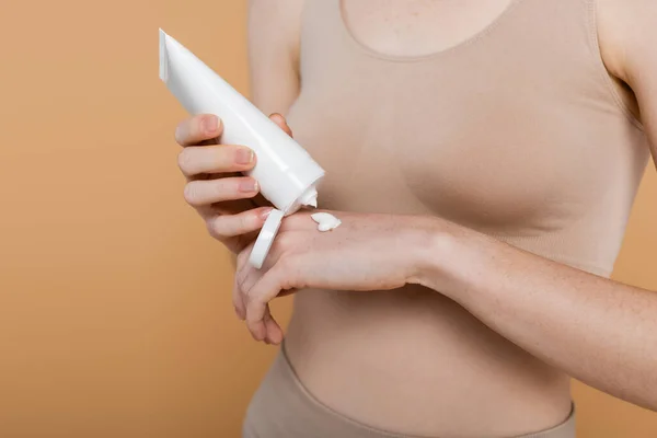 Обрізаний вид жінки, що наносить крем на руку ізольовано на бежевий — стокове фото