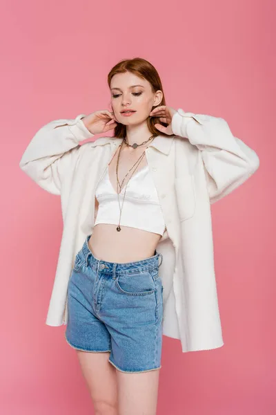 Jolie femme rousse en veste et chemises en denim posant isolée sur rose — Photo de stock