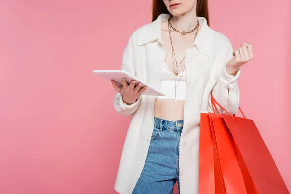 Vista ritagliata di donna elegante che tiene borse della spesa e tablet digitale isolato su rosa — Foto stock