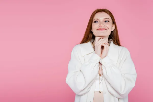 Pleased red haired woman in necklaces and jacket isolated on pink — Stock Photo