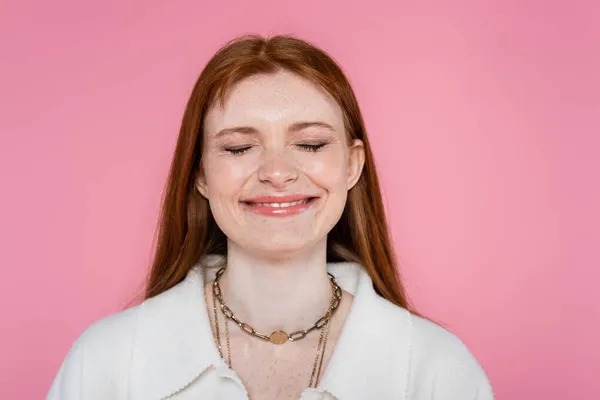 Felice lentigginoso donna chiusura occhi e sorridente isolato su rosa — Foto stock