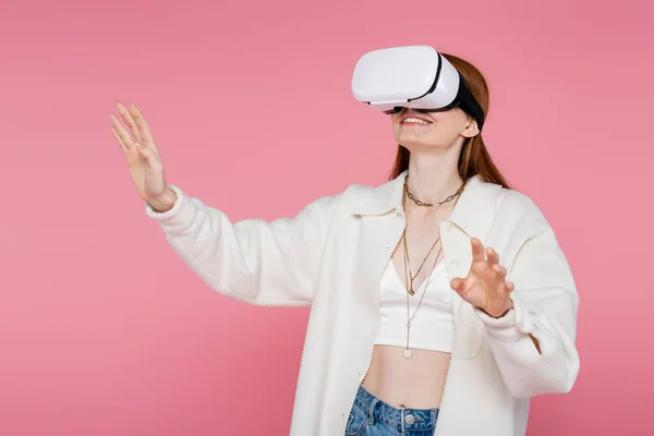 Mulher alegre e na moda em jogos de jaqueta no fone de ouvido vr isolado em rosa — Fotografia de Stock