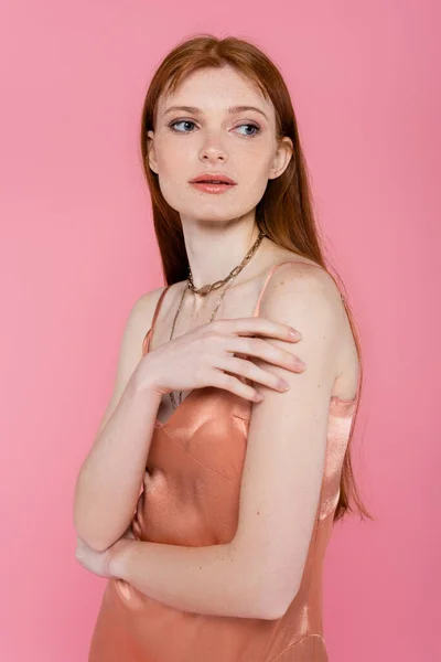 Red haired woman in silk dress posing isolated on pink — Stock Photo