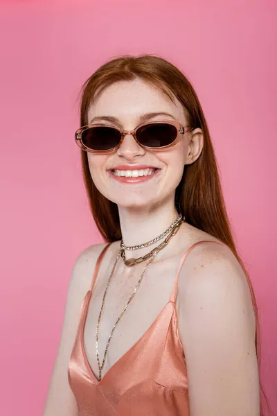 Portrait de femme aux taches de rousseur élégant dans des lunettes de soleil isolées sur rose — Photo de stock