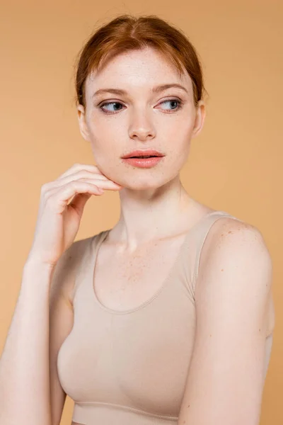 Freckled woman in top touching face isolated on beige — Stock Photo