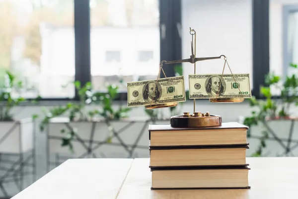 QUIIV, UCRÂNIA - SETEMBRO 22, 2021: escalas de justiça com notas de dólar em livros de escritório, conceito anti-corrupção — Fotografia de Stock