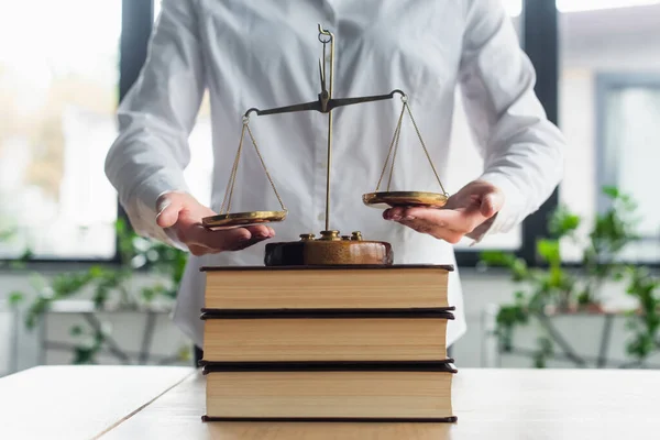 Cropped view of businesswoman near justice scales on books in office, anti-corruption concept — Stock Photo