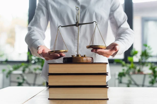 Cropped view of businesswoman near justice balances on books in office, concept anti-corruption — Photo de stock