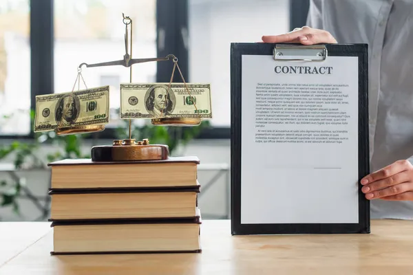 KYIV, UKRAINE - SEPTEMBER 22, 2021: partial view of businesswoman holding contract near justice scales with money, anti-corruption concept — Stock Photo