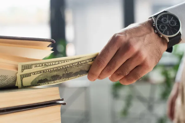 Cropped view of lawyer hiding dollar banknotes into codex book, anti-corruption concept — Stock Photo