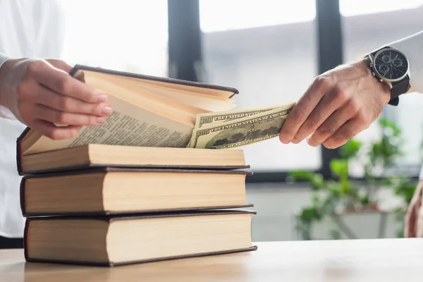 Partial view of lawyer putting dollars into codex book near client, anti-corruption concept — Stock Photo