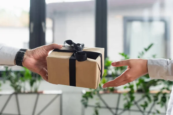 Vista recortada de hombre de negocios dando caja de regalo a la mujer en el cargo, concepto anticorrupción - foto de stock